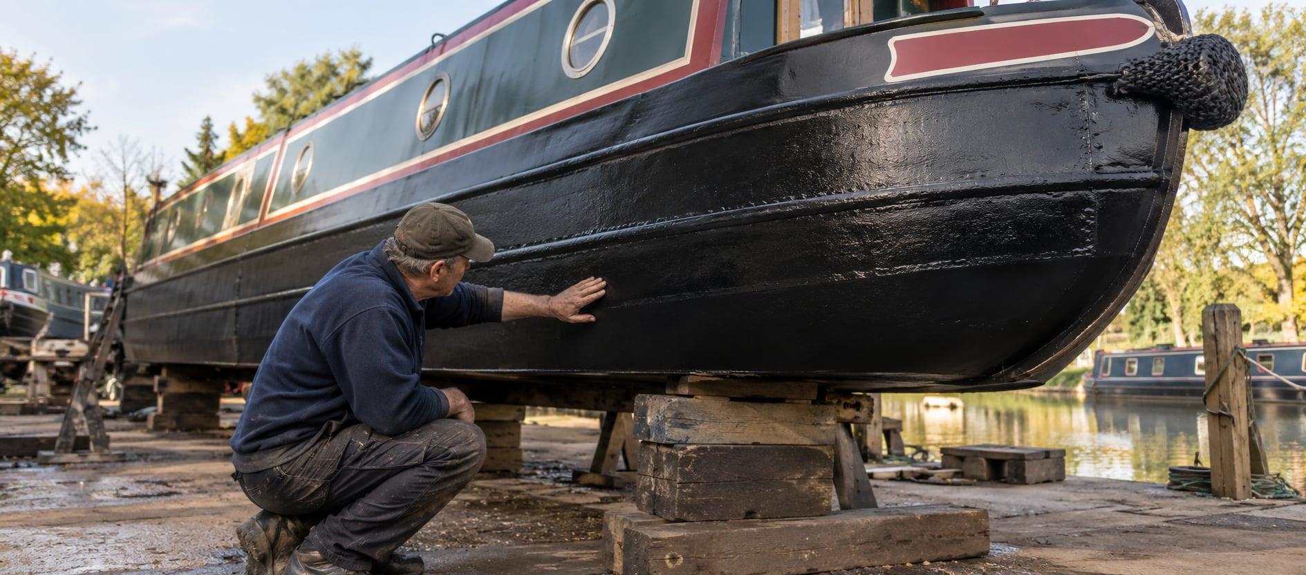 A narrowboat out of the water, its hull being checked